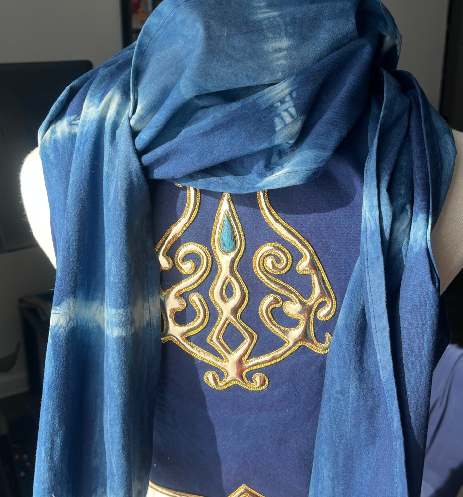 work in progress for a monster hunter cosplay. it is the back of a blue vest with gold work embroidery 